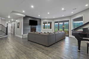 Living area featuring dark wood finished floors, stairs, baseboards, recessed lighting, and a large fireplace