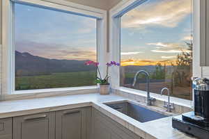 Kitchen featuring a sink, gray cabinetry, a mountain view, and light stone countertops
