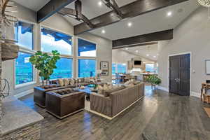 Living area featuring high vaulted ceiling, beamed ceiling, baseboards, hardwood / wood-style flooring, and a ceiling fan