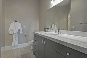 Bathroom with toilet, vanity, tile patterned flooring, and baseboards