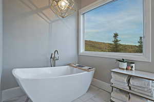 Full bathroom with marble look tiles, healthy amount of natural light, a soaking tub, and baseboards