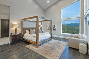 Bedroom with high vaulted ceiling, dark wood-type flooring, multiple windows, baseboards, and recessed lighting