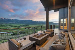 Deck at dusk featuring an outdoor living space with a fire pit, a mountain view, and a view of countryside