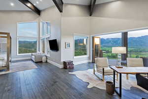 Living area with beam ceiling, dark wood-type flooring, plenty of natural light, and high vaulted ceiling