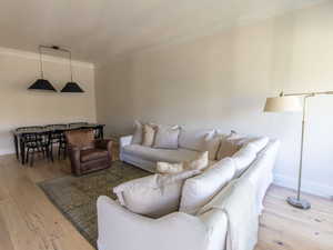 Living area featuring crown molding, wood-type flooring, and baseboards