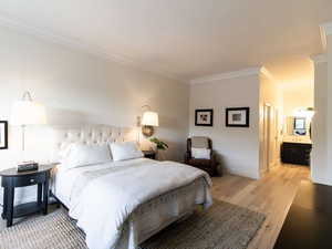 Bedroom featuring crown molding, light wood-style floors, baseboards, and ensuite bathroom