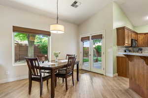 Dining space with vaulted ceiling, light wood finished floors, healthy amount of natural light, and baseboards