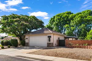 View of front of property featuring stone siding, a garage, a gate, driveway, and stucco siding