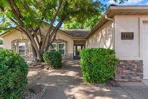 Property entrance featuring stone siding, stucco siding, and a tiled roof