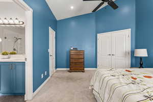 Bedroom with light carpet, baseboards, a closet, ensuite bathroom, and a sink