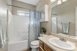 Bathroom with shower / bathtub combination with curtain, vanity, and toilet