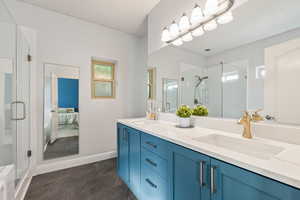 Full bathroom with a shower stall, marble finish floors, double vanity, and baseboards