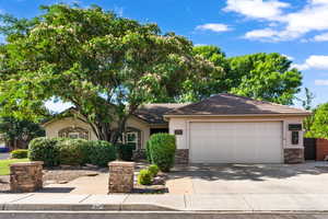 View of front of property with stucco siding, driveway, a garage, and stone siding