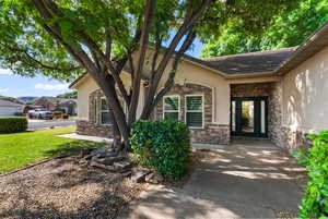 Property entrance featuring stone siding, stucco siding, a tile roof, and a lawn