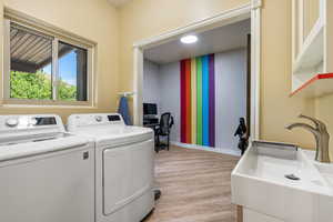 Washroom with light wood-type flooring, baseboards, and independent washer and dryer