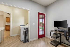 Home office featuring light wood-style floors, washing machine and clothes dryer, and baseboards