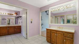 Full bathroom with two vanities, tile patterned floors, and baseboards