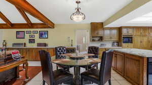 Dining space with light tile patterned floors and beam ceiling