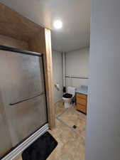 Bathroom featuring a stall shower, toilet, and vanity