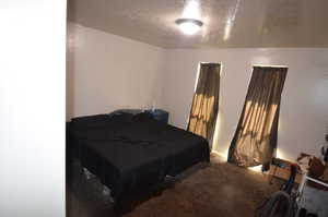 Carpeted bedroom featuring a textured ceiling