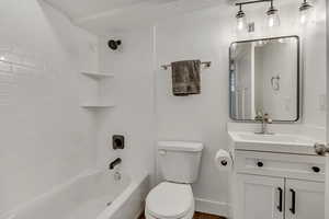 Bathroom with vanity, bathtub / shower combination, toilet, and baseboards