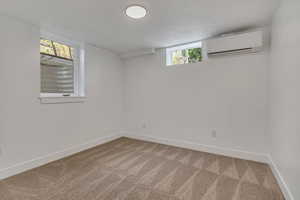 Basement featuring an AC wall unit, carpet flooring, and baseboards