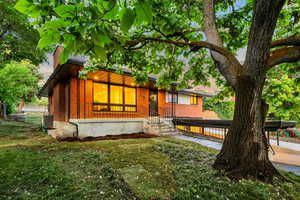 View of front facade featuring brick siding, a front lawn, a chimney, and central air condition unit