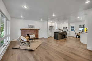 Living room with recessed lighting, baseboards, wood finished floors, and a fireplace