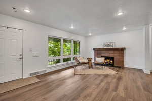 Living room featuring wood finished floors, a brick fireplace, recessed lighting, and baseboards