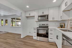Kitchen featuring stainless steel appliances, a sink, recessed lighting, light countertops, and white cabinets