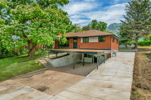 Rear view of house with driveway, a mountain view, a carport, brick siding, and a shingled roof