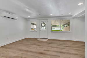 Entryway featuring a wall unit AC, recessed lighting, baseboards, and wood finished floors
