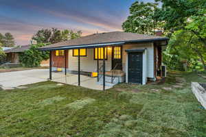Back of house with a chimney, a lawn, a patio area, and a shingled roof