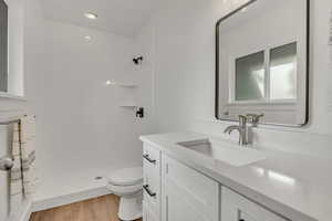 Full bath featuring vanity, a shower stall, toilet, wood finished floors, and recessed lighting