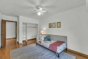 Bedroom with a closet, wood finished floors, baseboards, and ceiling fan
