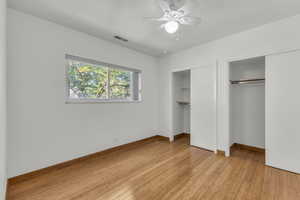 Unfurnished bedroom with two closets, light wood-type flooring, baseboards, and ceiling fan