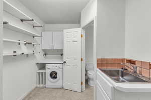 Washroom featuring washer / clothes dryer, light carpet, and baseboards