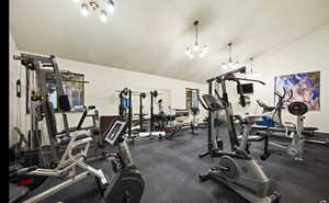 Gym featuring vaulted ceiling, a chandelier, and a textured ceiling