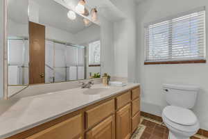 Full bathroom with vanity, toilet, an enclosed shower, baseboards, and tile patterned floors
