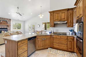 Kitchen with stainless steel dishwasher, under cabinet range hood, a sink, double wall oven, and a ceiling fan