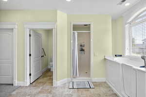 Bathroom featuring a stall shower, toilet, a bath, baseboards, and recessed lighting