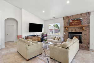Living room with arched walkways, recessed lighting, a fireplace and lofted ceilings