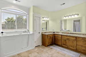 Bathroom featuring double vanity and a tub