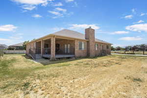 Rear view of property featuring brick siding, a chimney, and a covered patio