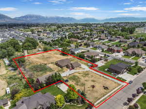 Aerial view of residential area featuring a mountain backdrop and property parcel outlined