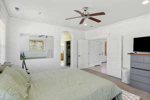 Master bedroom featuring crown molding, arched walkways, recessed lighting, and ceiling fan