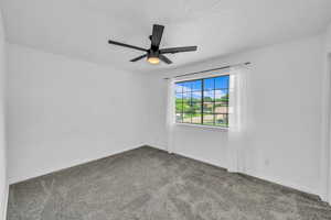 Carpeted empty room featuring ceiling fan, baseboards, and a textured ceiling