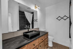 Full bath featuring toilet, tile patterned flooring, vanity, curtained shower, and baseboards
