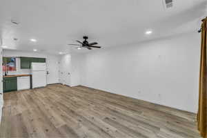 Unfurnished living room featuring recessed lighting, a ceiling fan, light wood-style flooring, baseboards, and a sink