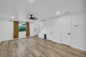 Unfurnished living room with stairway, ceiling fan, wood finished floors, recessed lighting, and baseboards